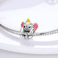 Charm éléphant gris aux grandes oreilles roses, détail jaune sur la tête, monté sur bracelet argenté.
