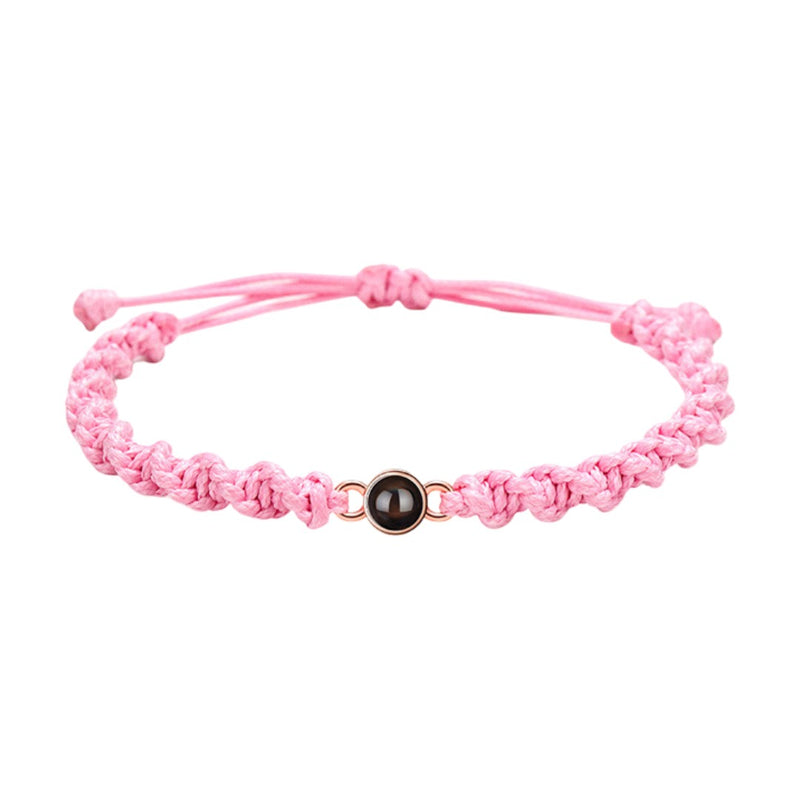 Bracelet tressé en nylon rose avec perle noire centrale et fermoir coulissant ajustable.