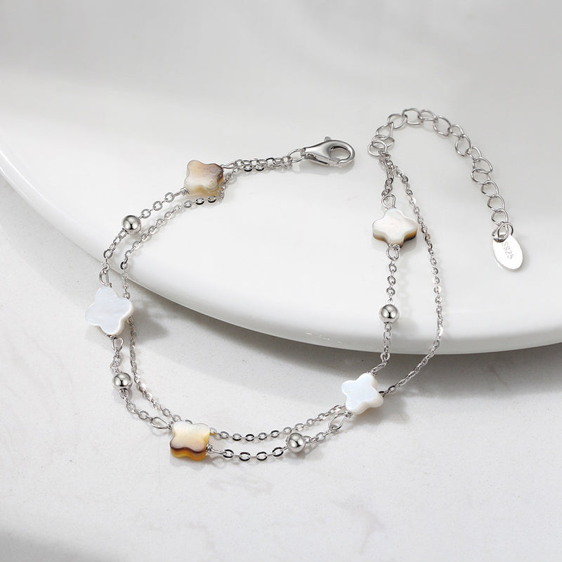 Bracelet double chaîne en argent 925 avec quatre trèfles en nacre blanche et noire délicate.