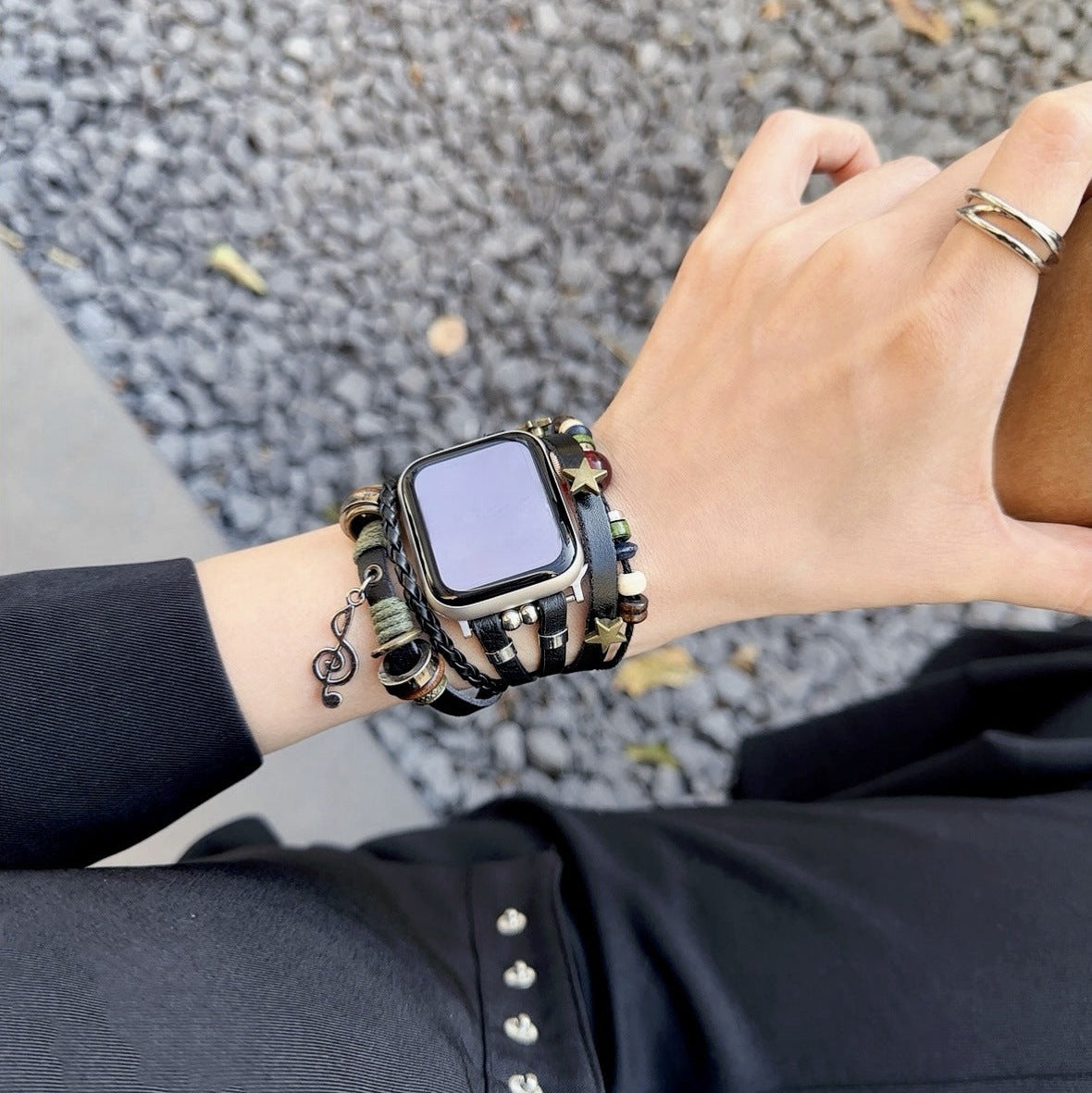 Bracelet Apple Watch tressé en simili cuir noir avec perles fantaisie dorées et pendentif musical, fermoir acier inoxydable.