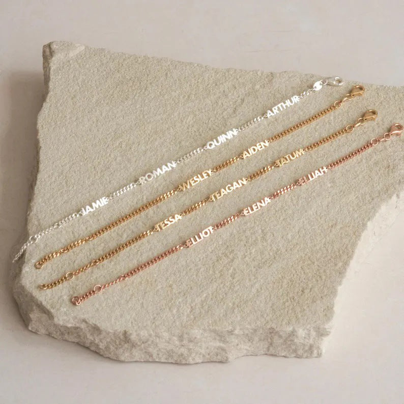 Quatre bracelets personnalisés en acier inoxydable avec prénoms taillés, mailles cubaines fines en argent, or rose et or.