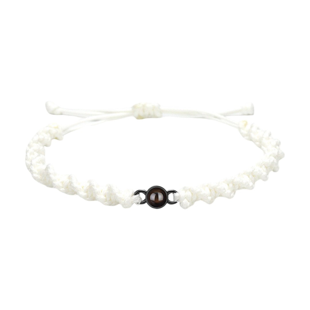 Bracelet tressé en nylon blanc avec fermoir coulissant noir et perle centrale marron.