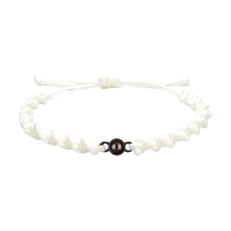 Bracelet tressé en nylon blanc avec fermoir coulissant noir et perle centrale marron.