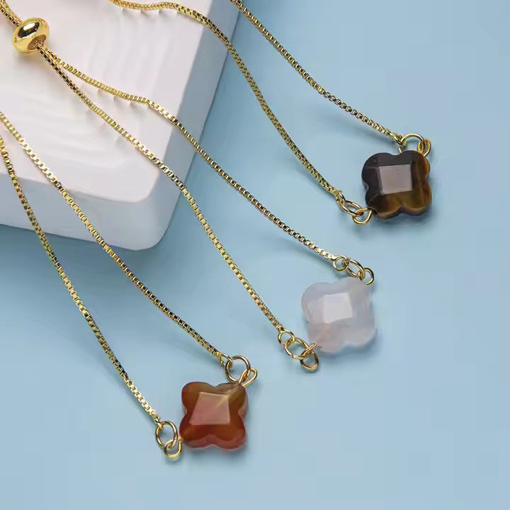 Trois bracelets à cordon doré avec pierres naturelles taillées en trèfle, tons brun, beige et noir, fermoir coulissant doré.