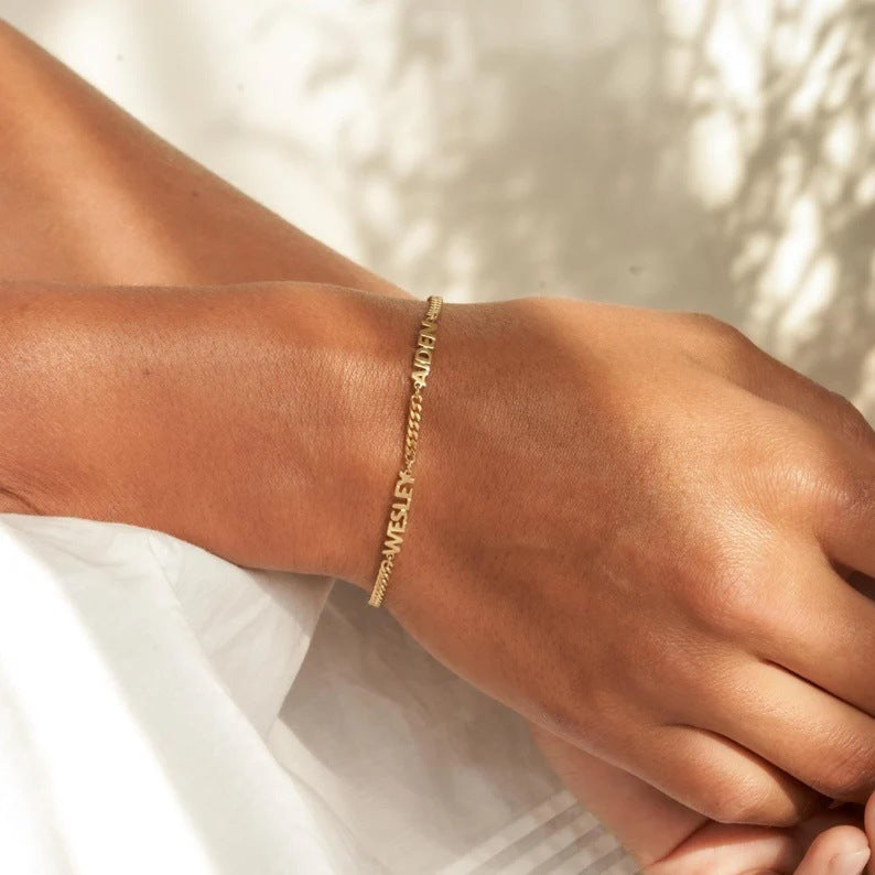 Bracelet fin en acier inoxydable doré, chaîne maille cubaine avec quatre prénoms taillés en relief, style élégant et moderne.