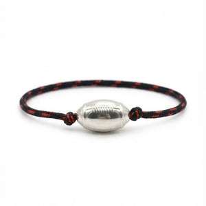 Bracelet cordon noir et rouge avec pendentif en forme de ballon de rugby argenté brillant.