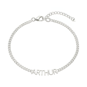 Bracelet fin en acier inoxydable argenté avec prénom "ARTHUR" en lettres découpées, chaîne maille cubaine et fermoir.