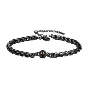 Bracelet maille tressée en acier inoxydable noir avec perle centrale brillante et fermoir réglable.