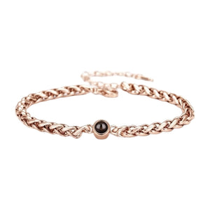 Bracelet maille tressée en acier inoxydable couleur or rose avec perle noire centrale et fermoir réglable.