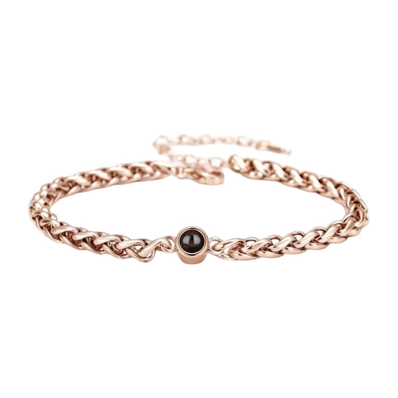 Bracelet maille tressée en acier inoxydable couleur or rose avec perle noire centrale et fermoir réglable.