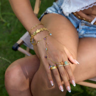 Bracelet chaîne doré avec pierres naturelles colorées porté au poignet et bagues assorties fines en acier inoxydable.
