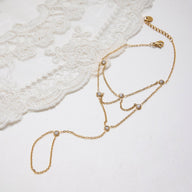 Bijou de main doré en acier inoxydable avec chaînes fines et pierres scintillantes élégantes.