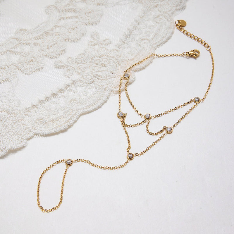 Bijou de main doré en acier inoxydable avec chaînes fines et pierres scintillantes élégantes.