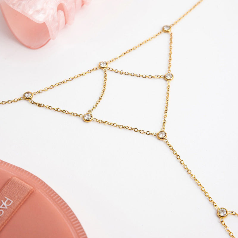 Bijou de main doré en acier inoxydable avec chaînes fines et pierres scintillantes rondes, design élégant et délicat.