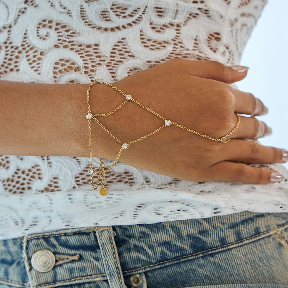 Bijou de main doré en acier inoxydable avec chaînes fines et pierres scintillantes délicates, style chic et aérien.