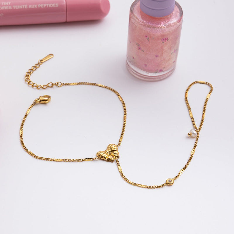 Bijou de main doré en acier inoxydable avec chaîne maille cubaine, papillon orné de zircons et perles fines.