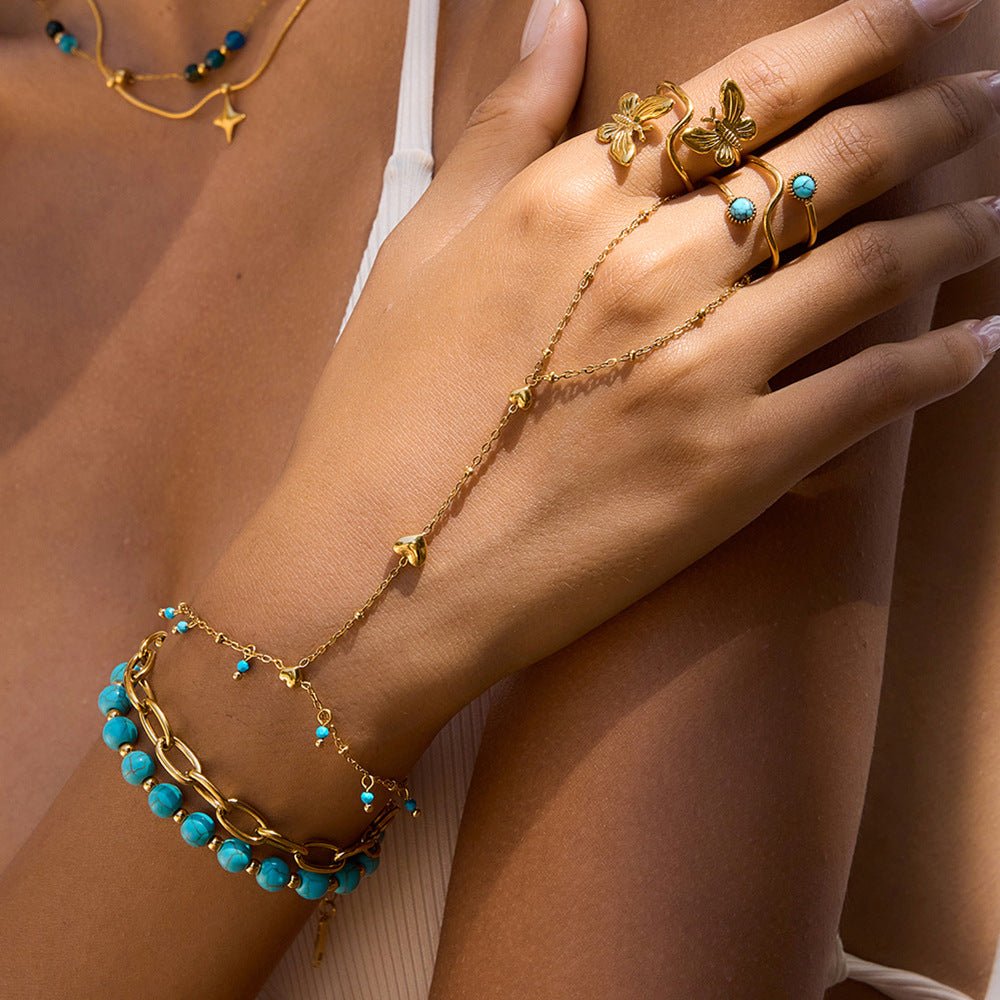 Bijou de main doré en acier inoxydable avec perles turquoise et chaînette en forme de cœur.