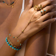 Bijou de main doré en acier inoxydable avec perles turquoise et chaînette en forme de cœur.