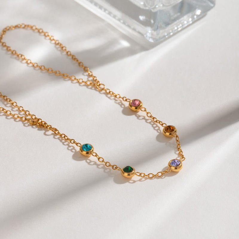 Chaîne fine dorée avec pierres de zirconium colorées brillantes, style délicat et élégant.