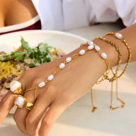 Bijou de main en acier inoxydable doré avec chaîne fine ornée de perles blanches, style chic et moderne.