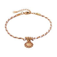 Bracelet fin en coton rose et acier inoxydable doré avec fleur centrale dentelée.