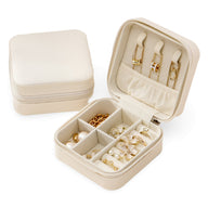 Boîte à bijoux nomade Oria beige avec compartiments et porte-bagues intégré.