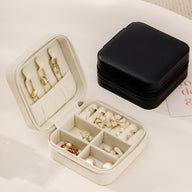 Boîte à bijoux voyage beige avec compartiments et porte-bagues intégrés, design compact et élégant.