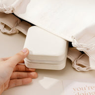 Boîte à bijoux nomade Oria blanche compacte avec coins arrondis tenue à la main.