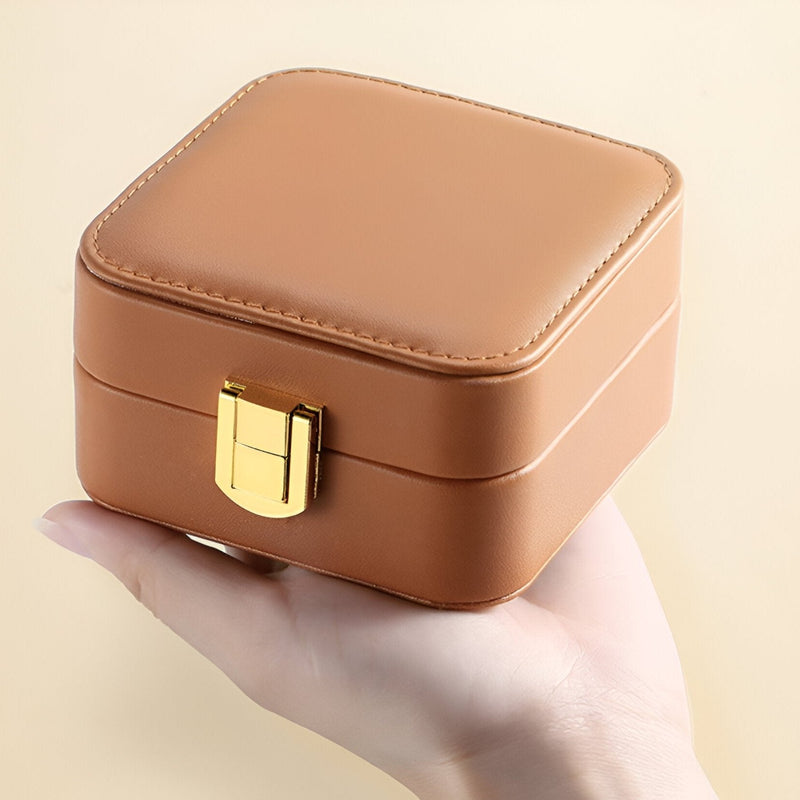 Boîte à bijoux nomade marron en cuir synthétique avec fermeture dorée, carré compact.
