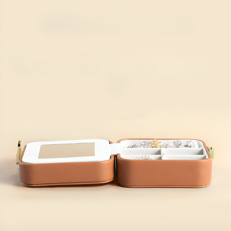 Boîte à bijoux nomade marron à double compartiment avec intérieur blanc et miroir, fermeture éclair dorée.