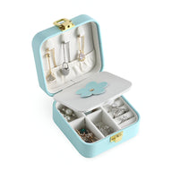 Boîte à bijoux nomade bleue à double compartiment avec fleur décorative et intérieur blanc doux.