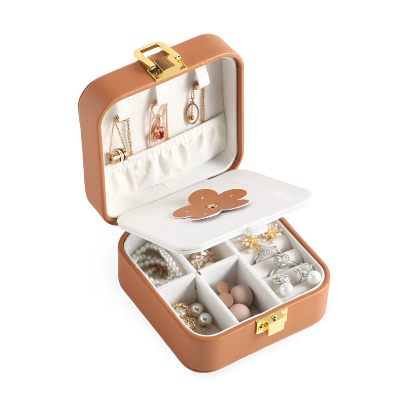 Boîte à bijoux nomade marron à double compartiment avec fleur en cuir apparente et intérieur blanc.