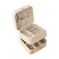 Boîte à bijoux nomade beige à double compartiment avec compartiments pour bagues, colliers et boucles d'oreilles.