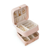 Boîte à bijoux nomade rose poudré à double compartiment avec rangements pour boucles d'oreilles, bagues et colliers.