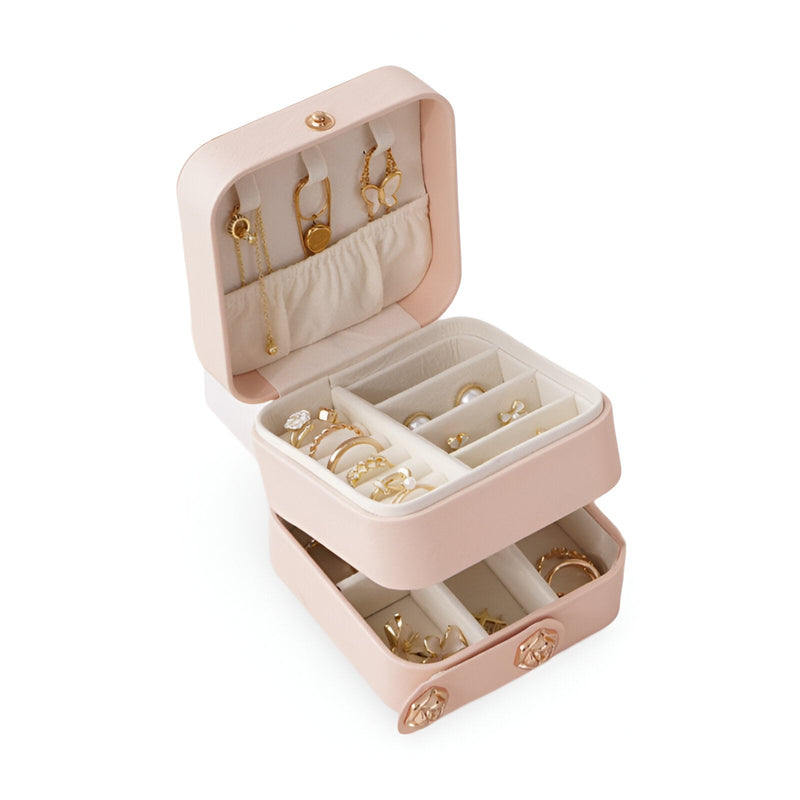 Boîte à bijoux nomade rose poudré à double compartiment avec rangements pour boucles d'oreilles, bagues et colliers.