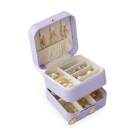 Boîte à bijoux nomade violette à double compartiment avec crochets dorés et séparateurs pour bagues et boucles d’oreilles.