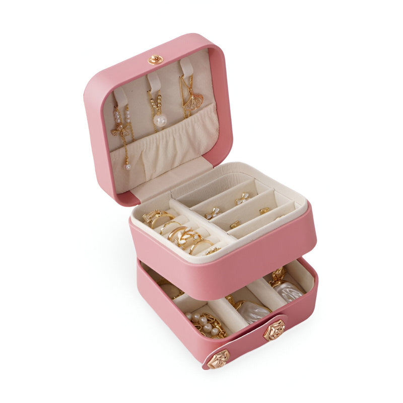 Boîte à bijoux nomade rose poudré à double compartiment avec rangements pour colliers, bagues et bracelets.