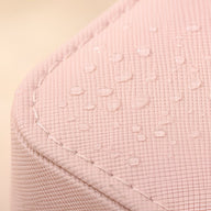 Coin arrondi d'une boîte à bijoux rose poudré avec texture croisée et gouttes d'eau visibles.