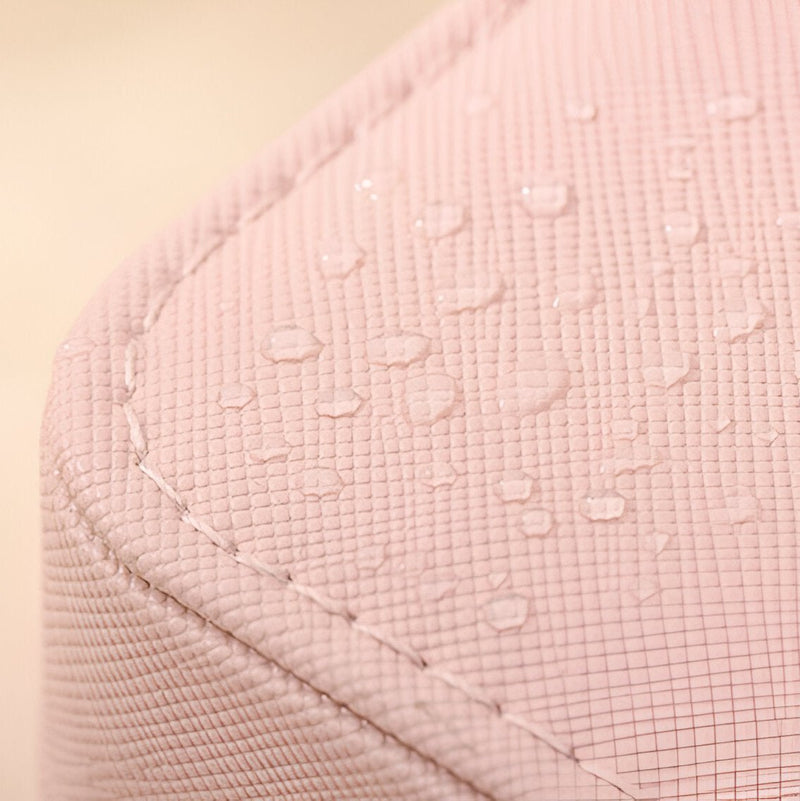 Coin arrondi d'une boîte à bijoux rose poudré avec texture croisée et gouttes d'eau visibles.