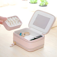 Boîte à bijoux rose nomade en simili cuir, intérieur compartimenté avec miroir et rangement amovible pour bagues.