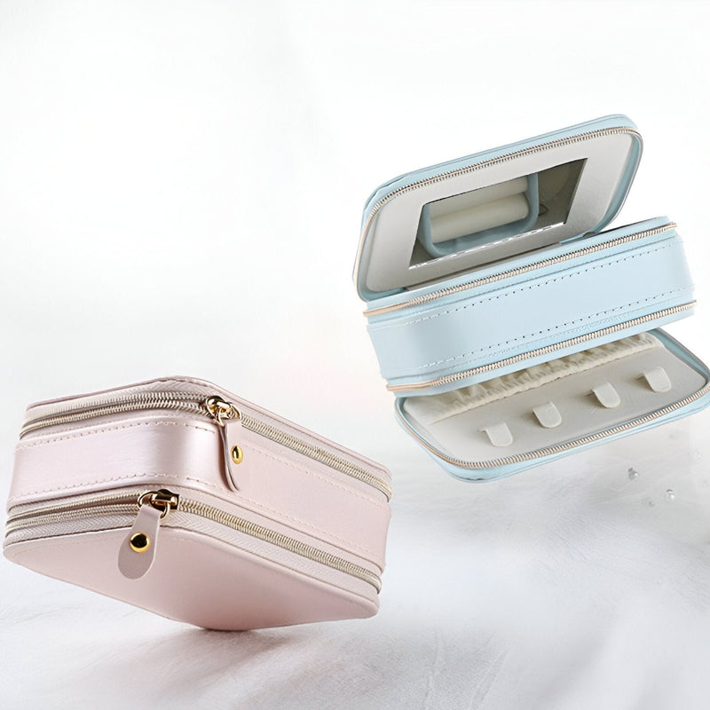 Boîte à bijoux nomade double fermeture éclair en cuir rose et bleu, intérieur organisé avec miroir et compartiments.