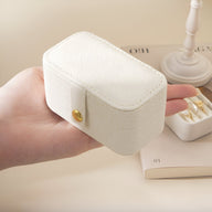 Boîte à bijoux nomade blanche en cuir grainé avec fermeture bouton-pression doré, format moyen.