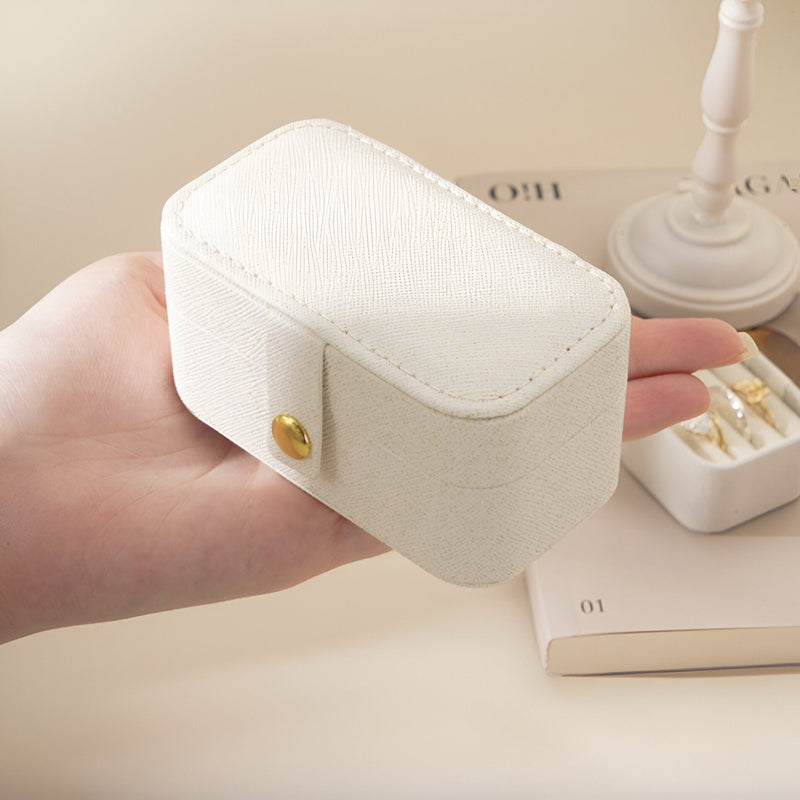 Boîte à bijoux nomade blanche en cuir grainé avec fermeture bouton-pression doré, format moyen.