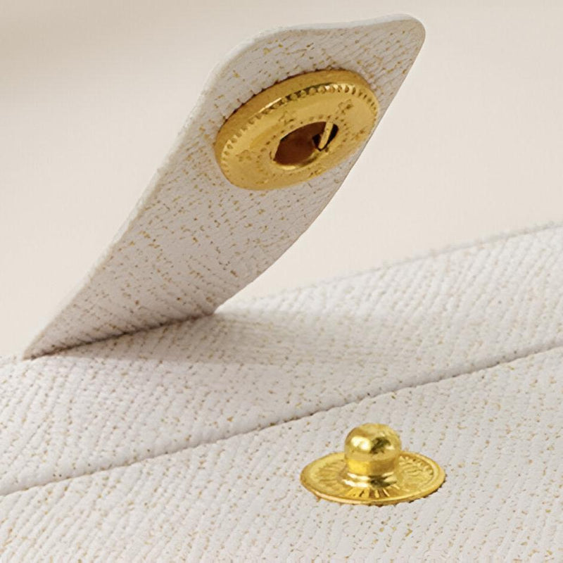 Fermoir bouton-pression doré sur boîte à bijoux nomade blanche texturée modèle Céleste.