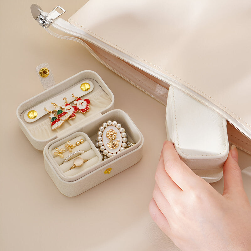 Boîte à bijoux nomade beige avec compartiments pour bijoux, fermoir aimanté et intérieur en velours.