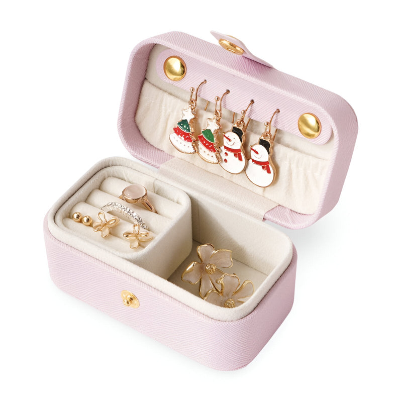 Boîte à bijoux nomade rose clair en cuir avec compartiments et boucles d'oreilles décoratives hiver.