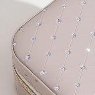 Boîte à bijoux nomade beige matelassée avec strass brillants et fermoir doré.