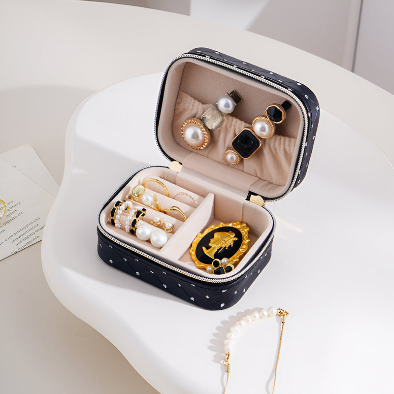 Boîte à bijoux nomade noire à strass avec compartiments pour bagues et boucles d’oreilles, intérieur beige doux.