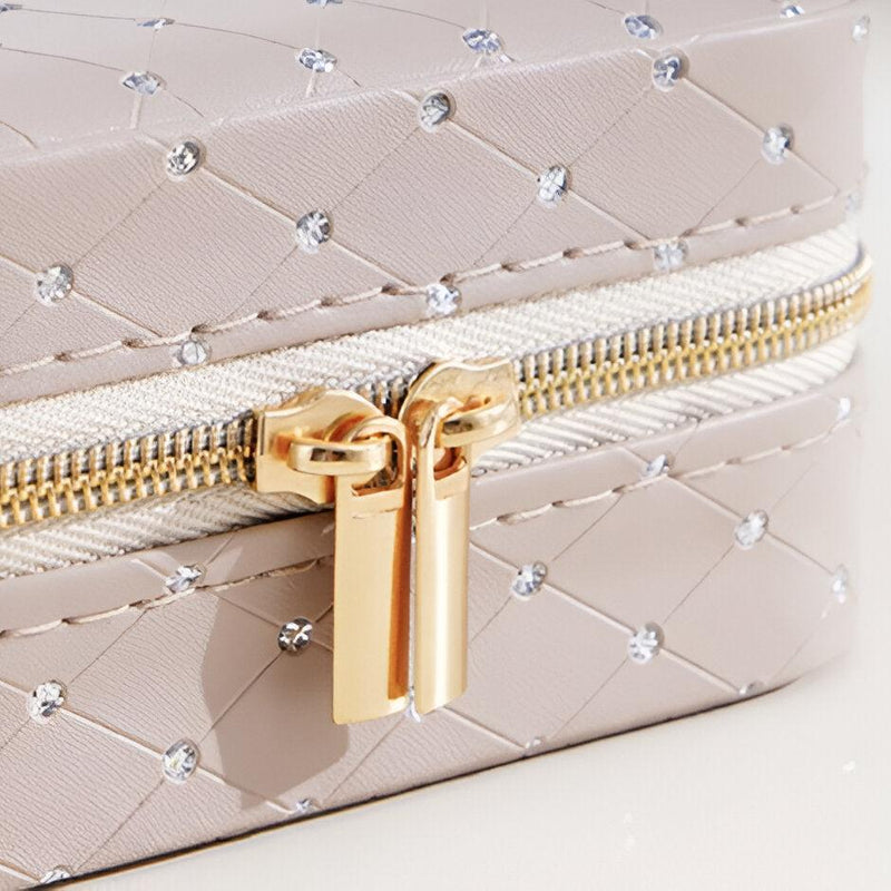 Boîte à bijoux beige matelassée avec strass, fermeture éclair or double curseur raffinée.