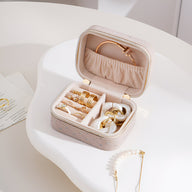 Boîte à bijoux beige nomade en velours avec intérieur organisé et fermoir strassé.